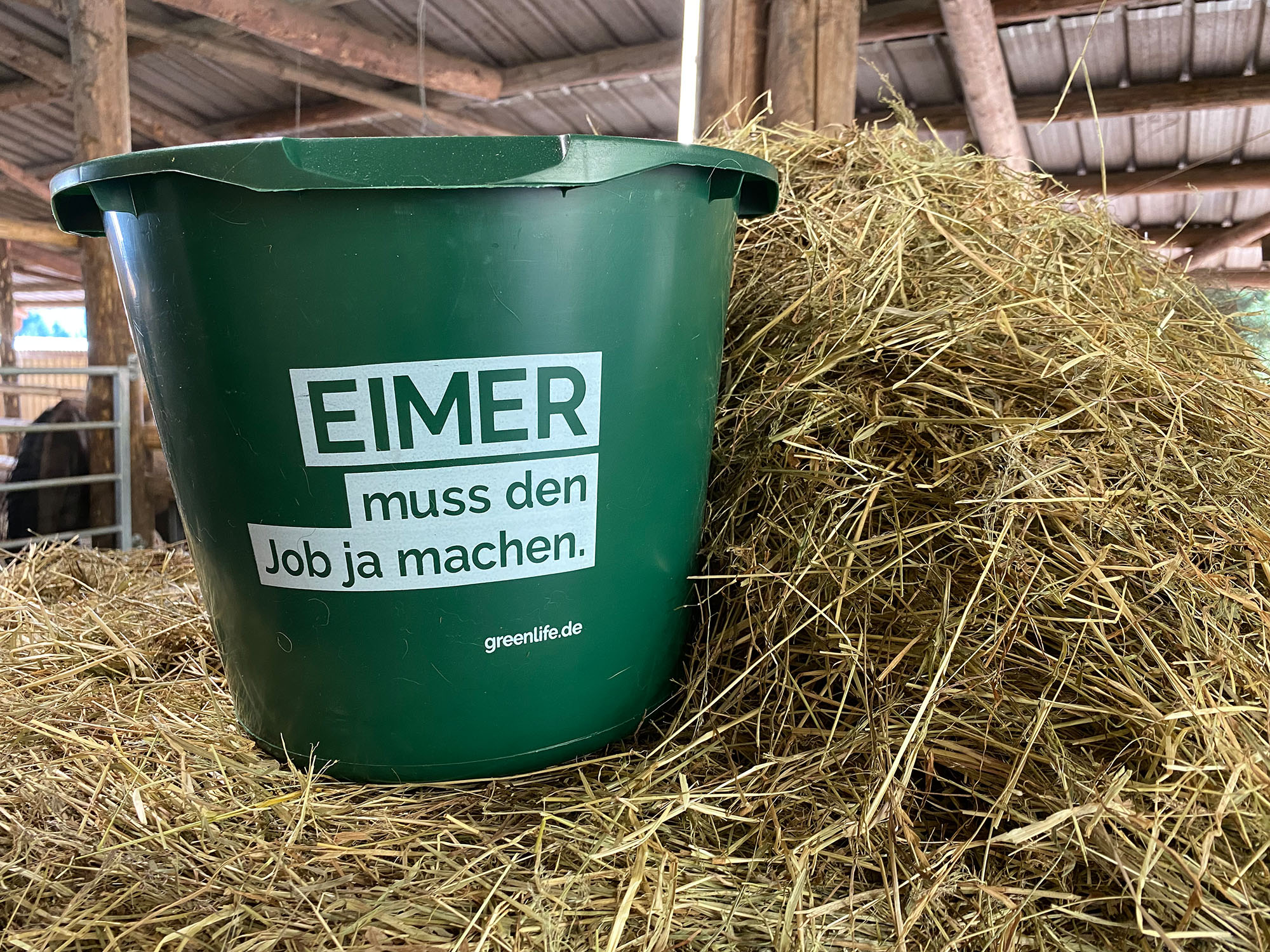Grüner 12 l Eimer mit Aufdruck 'Eimer muss den Job ja machen' im Einsatz auf einem Bauernhof von GreenLife